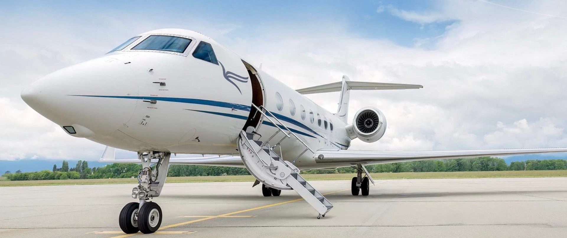 White private jet parked on runway with boarding stairs down under cloudy sky